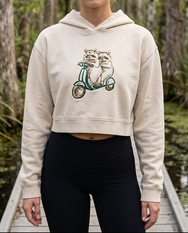 Light Apricot mineral wash crop hoodie with raccoon scooter graphic, front view, shown on a model.